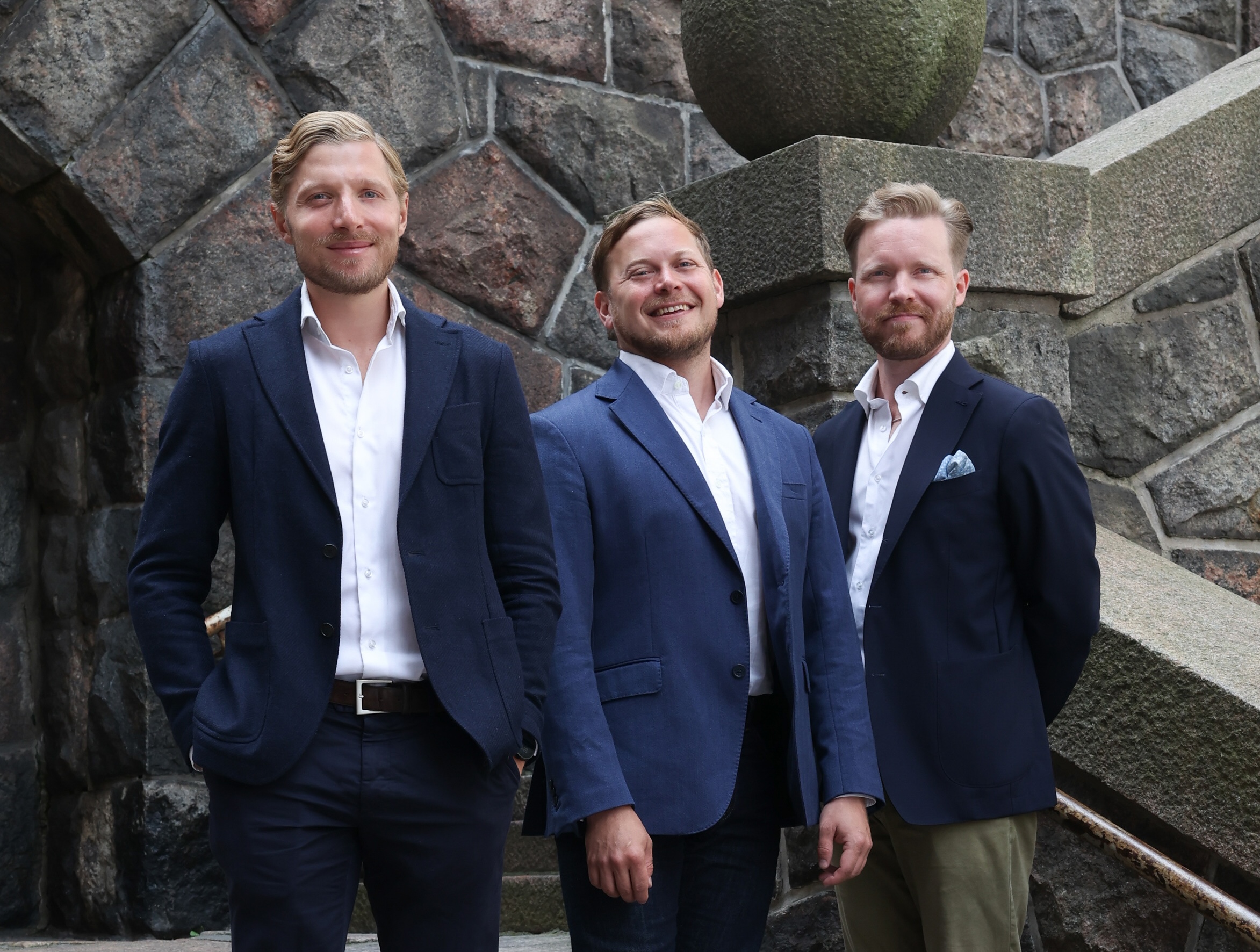 The DAL Partners team standing in front of a stone wall